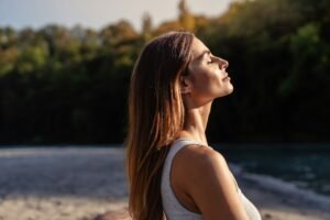 Young woman with long hair enjoying sun with closed eyes getting natural vitamin D