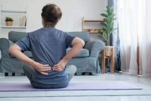 Elderly woman with back pain holding her lower back.