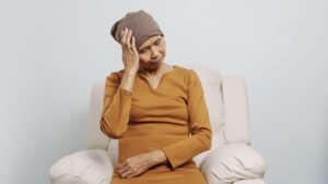 Mature woman suffering from cancer, asian people, 70s years old with head scarf, blue ribbon.